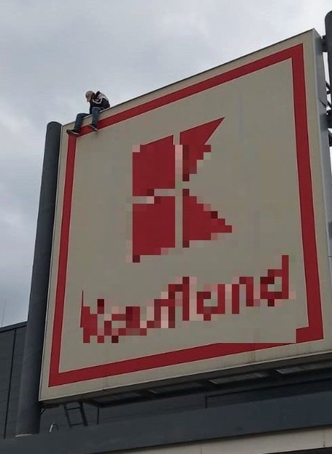 Zo strechy nákupného centra chce skočiť muž.