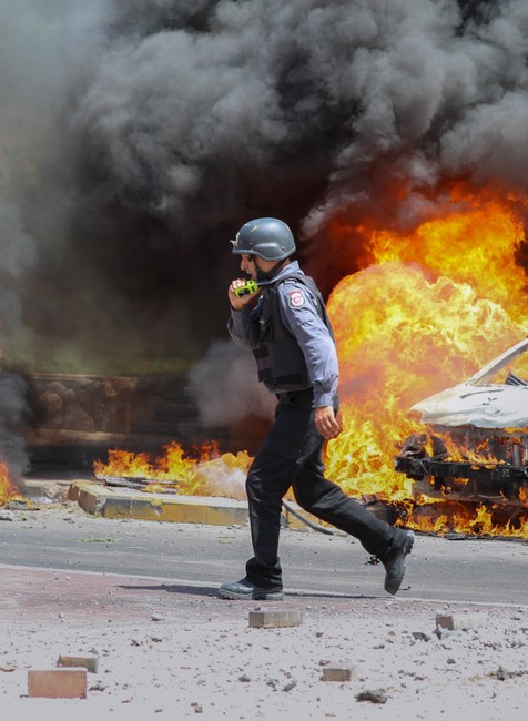 Izraelský hasič prechádzajúci vedľa automobilov zasiahnutých raketou