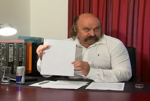 Mikuláš Vareha ukazuje dokumenty za pracovným stolom