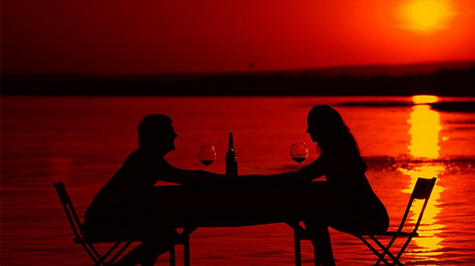 dvojica milenci na plazi, stol, vino, zapad slnka