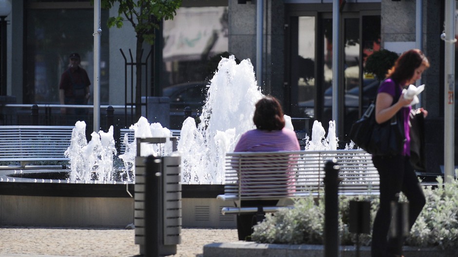 zena sedi pri fontane, druha ide s jedlom