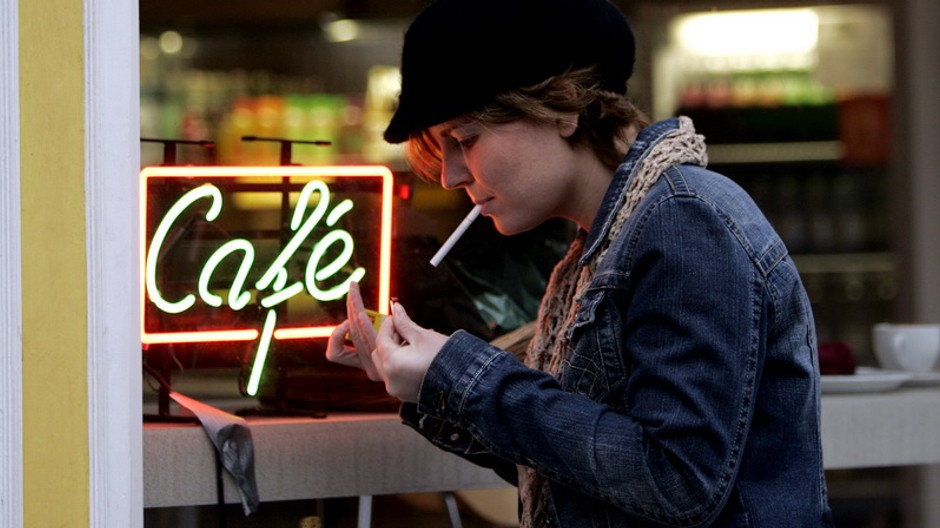 Fajčiarka si zapaľuje cigaretu pred kaviarňou